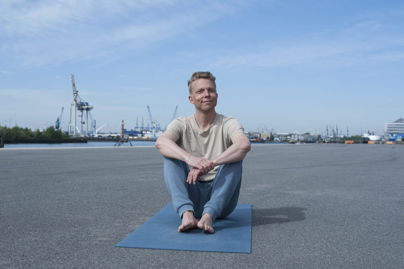 Jan Wolk sitzt im Schneidersitz auf einer Yogamatte am Hamburger Hafen.